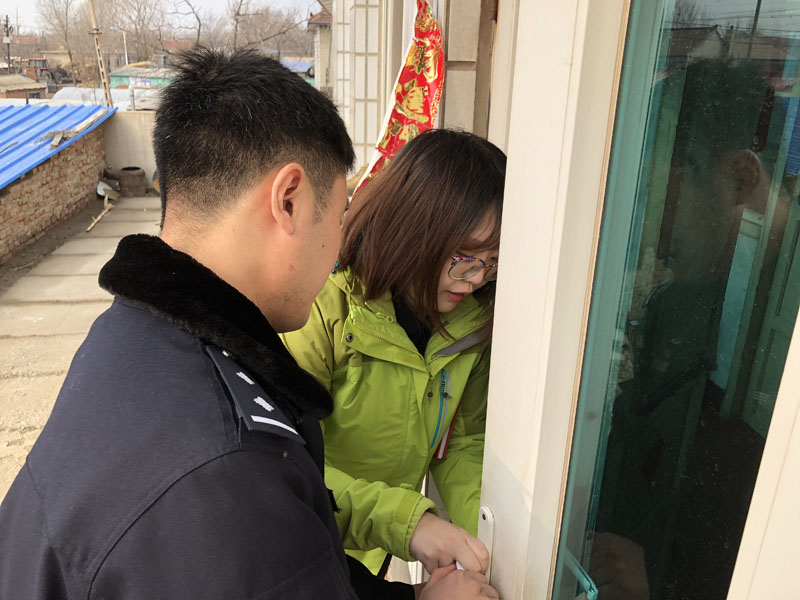 （图一）记者和民警一起查看报案者家中的门锁