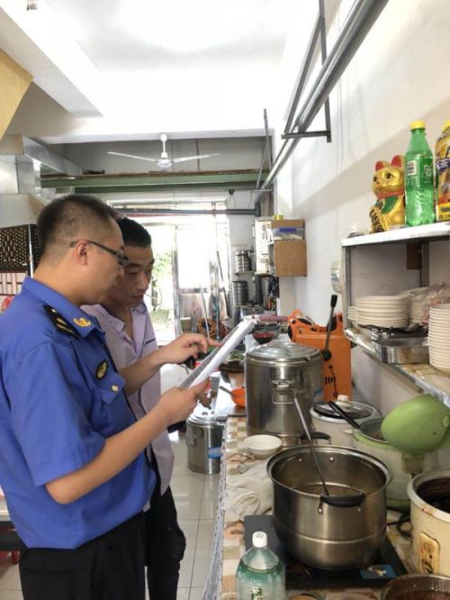综合执法人员对餐饮企业进行油烟污染检查