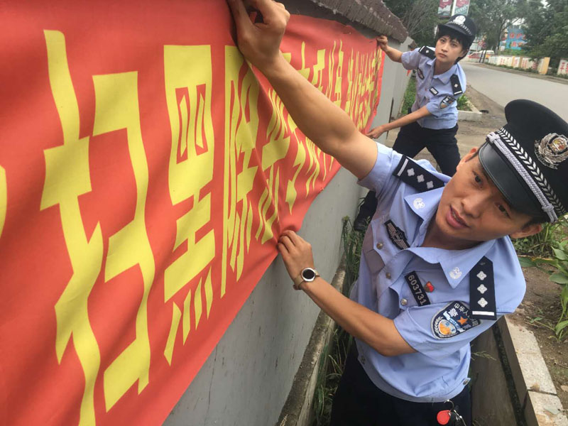 丹东市公安局振安分局同兴派出所民警在悬挂扫黑除恶宣传标语横幅。