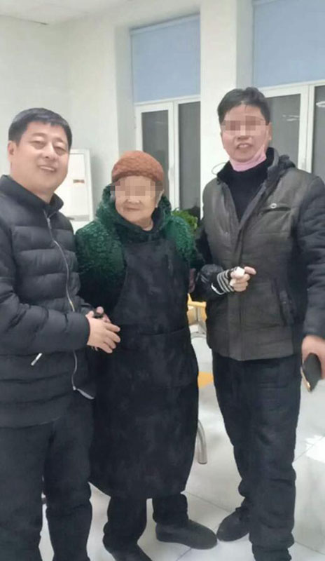 老人儿子（右）从民警（左）手中将老人接回家