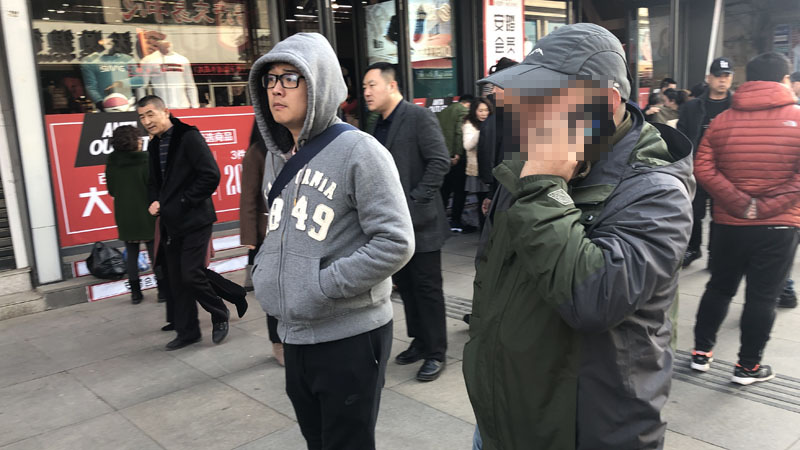 记者和王刚一起在步行街上寻找可疑人员（挡脸）