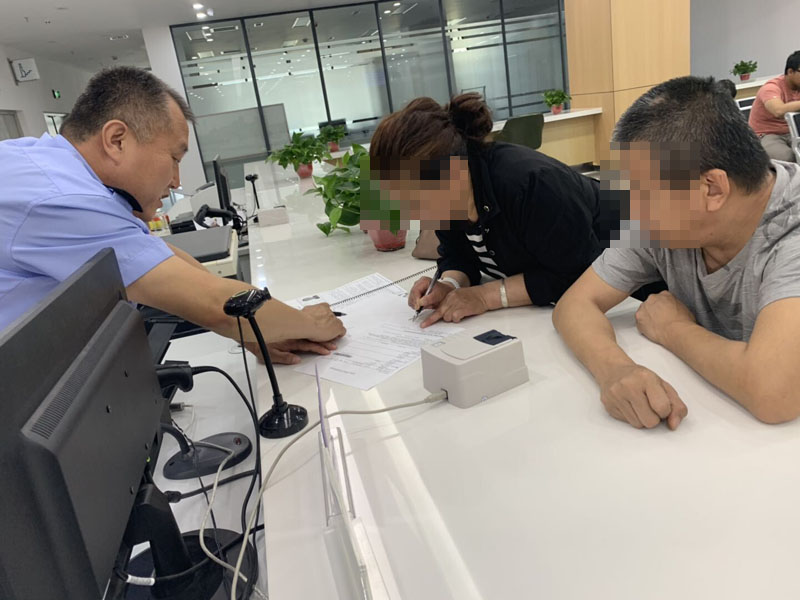 配文1：民警指导办理护照的残障人士手写签名