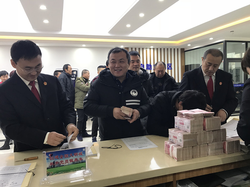 丁先生拿到被拖欠多年的工资款后露出久违的笑容