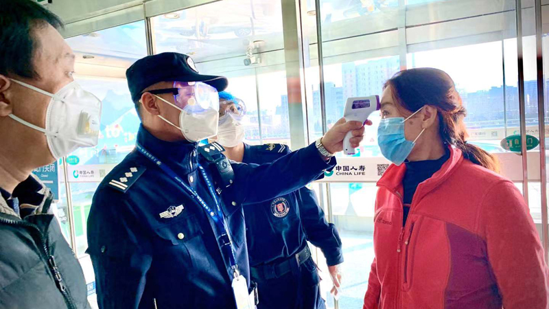 王鹏（左二）对旅客进行体温检测