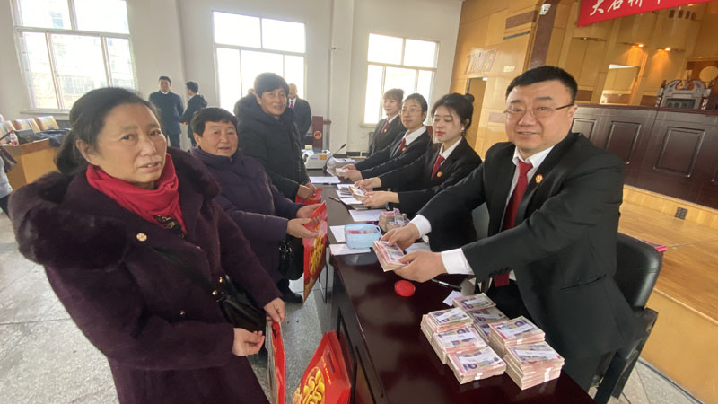 徐斌（左二）领取工资款；右一是大石桥市人民法院执行员王敬伟