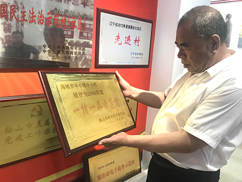 姜永波展示中小村获得的“一村一品示范村”牌匾