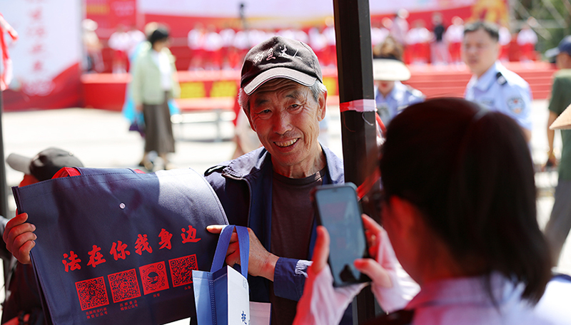 头题图,法治文艺节目展演活动现场,司法局工作人员发放原创普法购物袋。