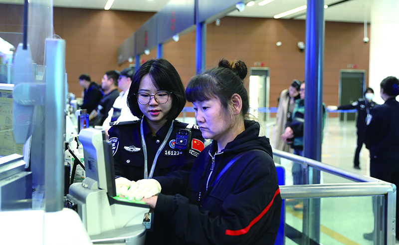 辽宁沈阳边检站移民管理警察帮助旅客录入指纹。