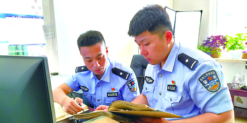 二题图，苏道博（右）同户籍民警王光硕正在查阅户籍老底卡，查找张先生户籍原始信息。受访者供图