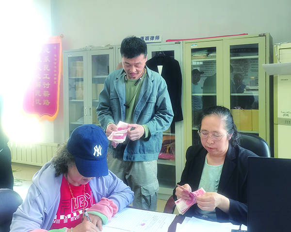 发放现场，付菊（右一）逐笔核对劳务费（受访单位供图）